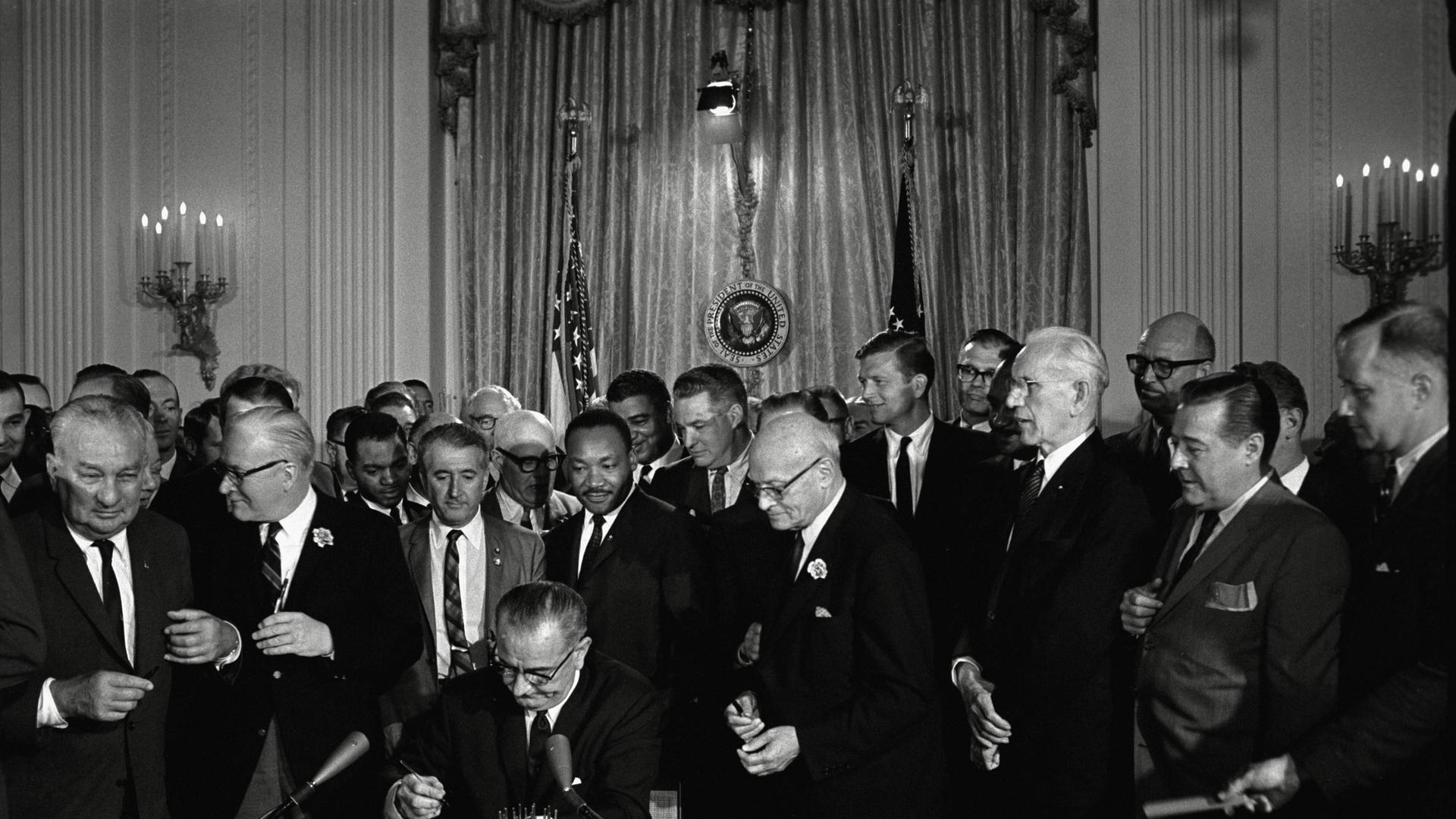 US-Präsident Lyndon Baines Johnson unterzeichnet das Bürgerrechtsgesetz (Civil Rights Act) von 1964, hinter dem Präsidenten steht Bürgerrechtler Martin Luther King
