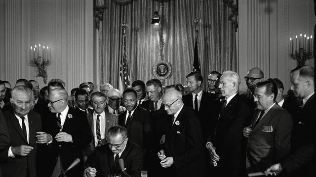 US-Präsident Lyndon Baines Johnson unterzeichnet das Bürgerrechtsgesetz (Civil Rights Act) von 1964, hinter dem Präsidenten steht Bürgerrechtler Martin Luther King