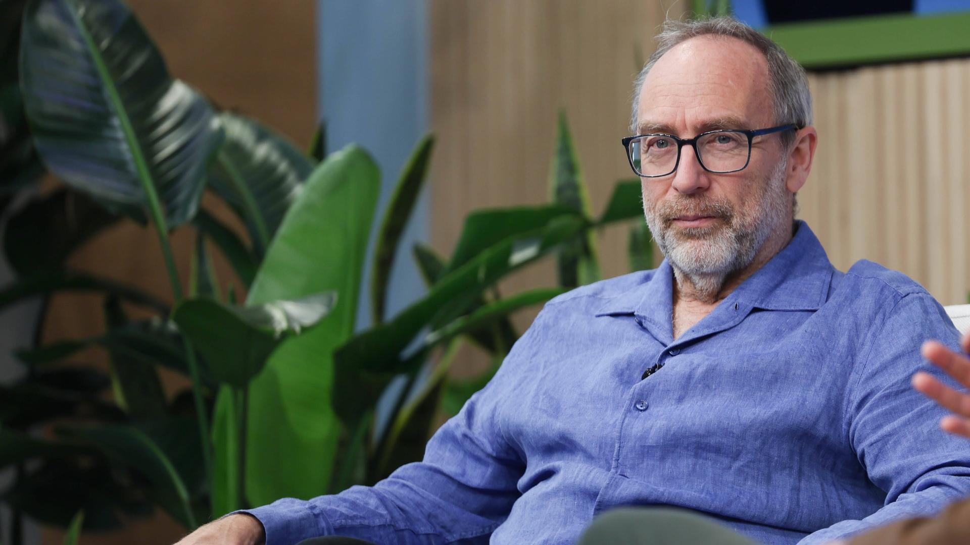 Jimmy Wales sitzt auf einer Bühne auf einem Sessel 