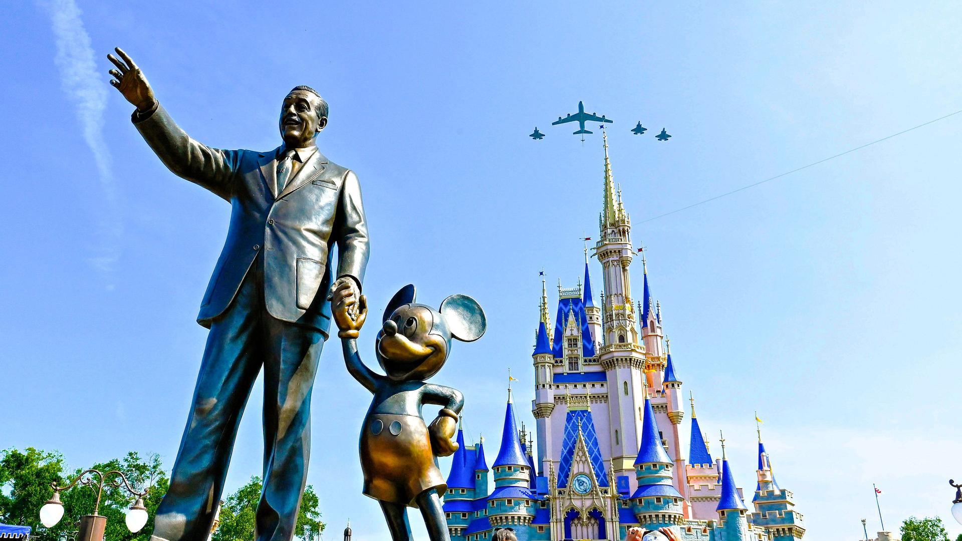 Eine Bronzestatue von Walt Disney und Mickey Mouse steht in Disney World Orlando vor dem Cinderellaschloss.