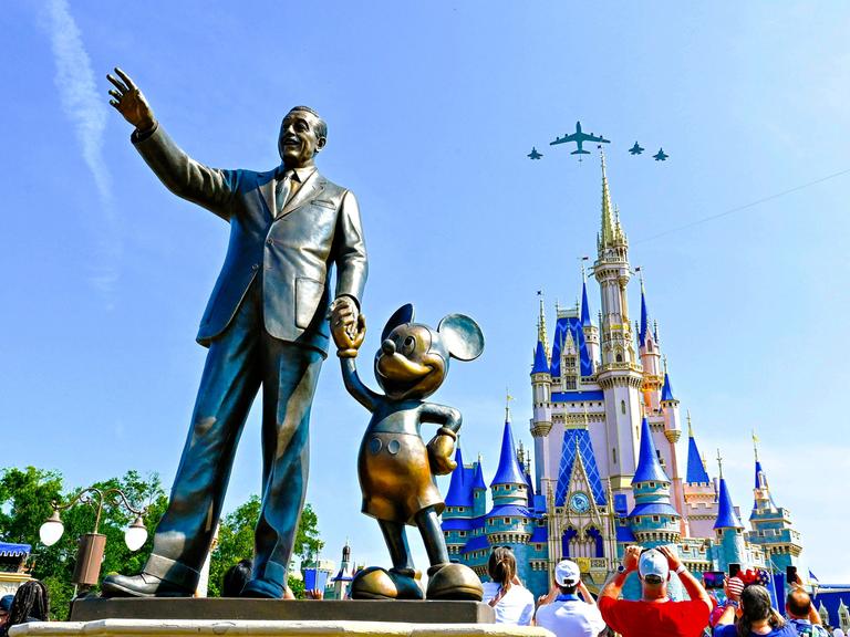 Eine Bronzestatue von Walt Disney und Mickey Mouse steht in Disney World Orlando vor dem Cinderellaschloss.