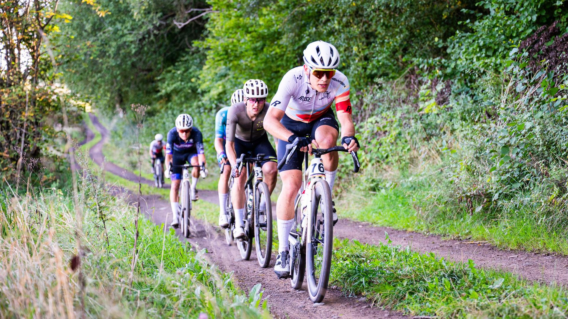 Mehrere Radfahrer fahren bei den Deutschen Gravel-Meisterschaften in der Vulkaneifel auf der Strecke. 