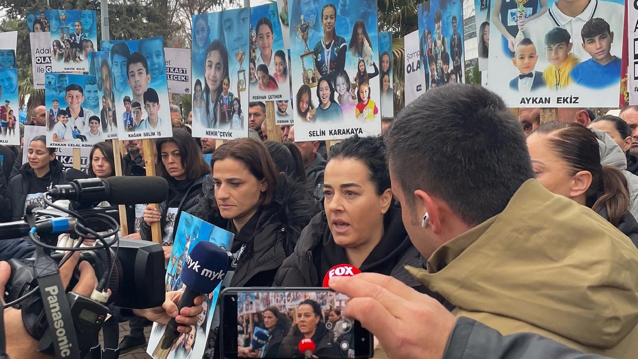 Angehörige stehen vor dem Gerichtsgebäude im südosttürkischen Adiyaman und halten Bilder ihrer Kinder hoch, dir bei dem Erdbeben im vergangenen Februar getötet wurden.