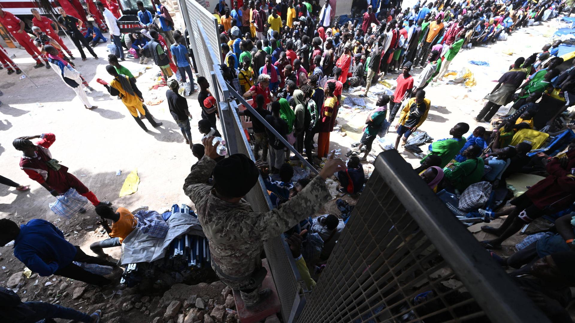 Hunderte Migrantinnen und Migranten stehen vor einem Tor einer Flüchtlingseinrichtung auf der italienischen Insel Lampedusa.