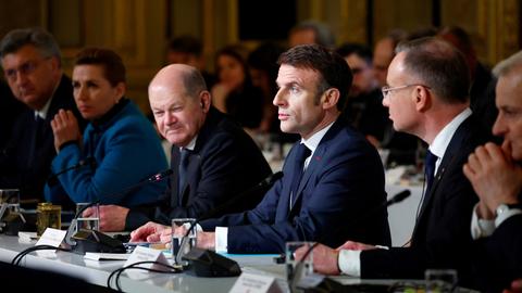 Der französische Präsident Emmanuel Macron, Mitte, hält eine Rede im Elysee-Palast in Paris am 26. Februar 2024. Links von ihm sitzt Bundeskanzler Olaf Scholz und blickt mit verkniffender Mine.