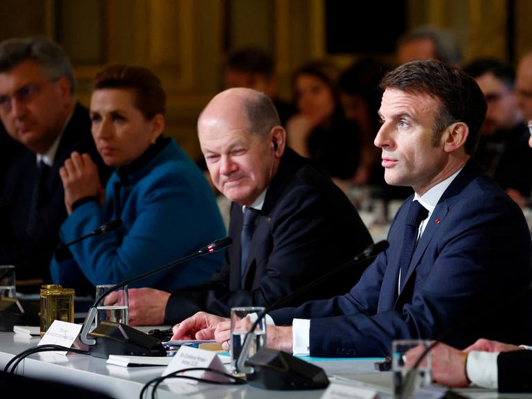 Der französische Präsident Emmanuel Macron, Mitte, hält eine Rede im Elysee-Palast in Paris am 26. Februar 2024. Links von ihm sitzt Bundeskanzler Olaf Scholz und blickt mit verkniffender Mine.
