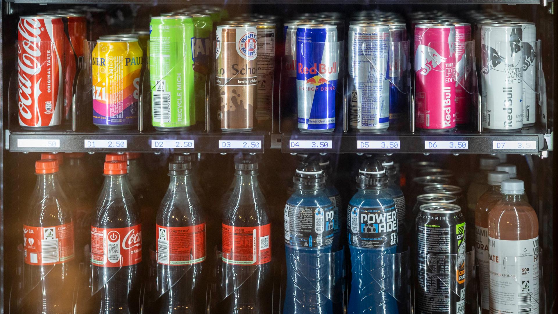 Eine Nahaufnahme eines Snackautomat in der Berliner U-Bahn Station Heidelberger Platz indem verschiedene Softdrinks und darüber Schokoriegel zu sehen sind.