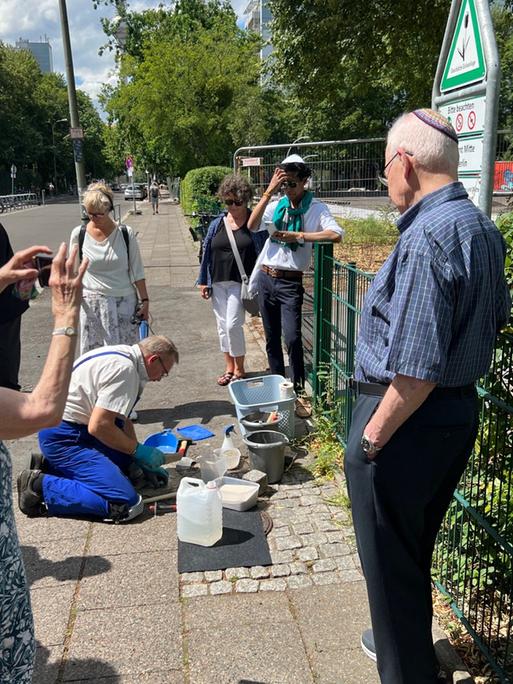 Thomas Schriever von der Stolpersteininitiative verlegt einen Stolperstein für Hans Lewinsohn im Beisein von Mitgliedern der Familie, die zum Teil aus den USA angereist waren.