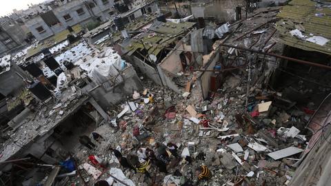Menschen inmitten durch einen israelischen Luftschlag zerstörter Häuser im südlichen Gazastreifen.
