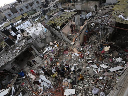 Menschen inmitten durch einen israelischen Luftschlag zerstörter Häuser im südlichen Gazastreifen. 