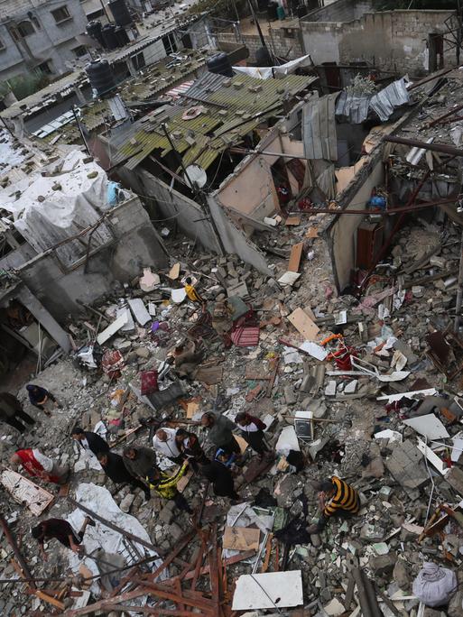 Menschen inmitten durch einen israelischen Luftschlag zerstörter Häuser im südlichen Gazastreifen. 