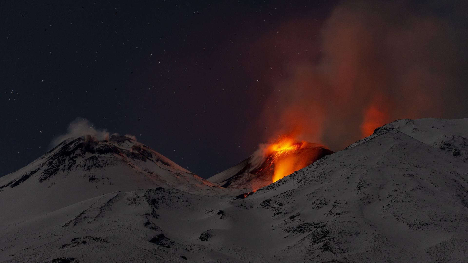 Zu sehen sind Lavafontänen im Vulkan Ätna auf Sizilien, es steigt Rauch auf.