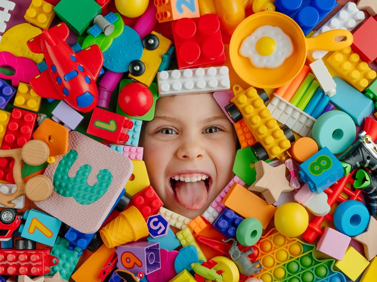 Gesicht eines lachenden Kindes  - von Lego- und anderen Bausteinen umgeben