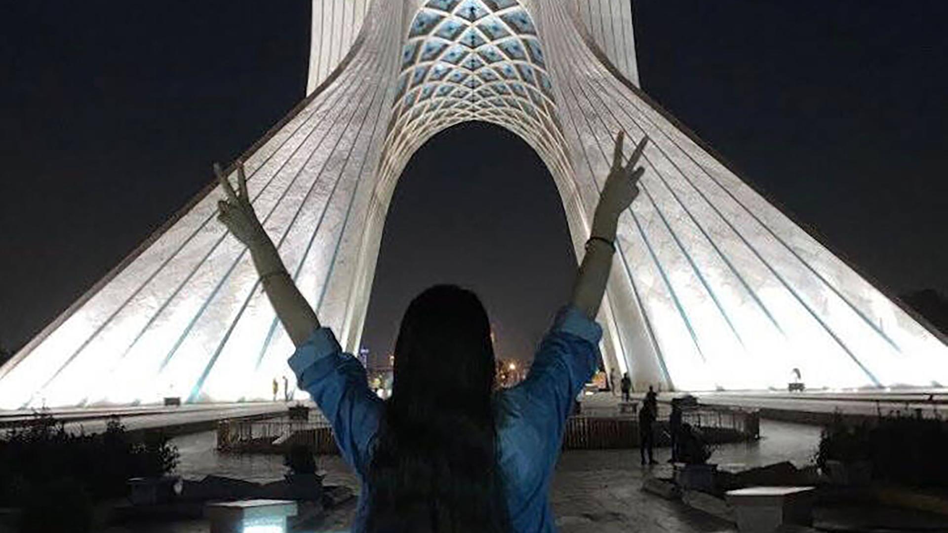 Eine junge Frau ohne Hijab mit offenen Haaren macht das Victoryzeichen mit ihren beiden Händen vor dem Azadi Turm in Teheran, 17.November 2022.
