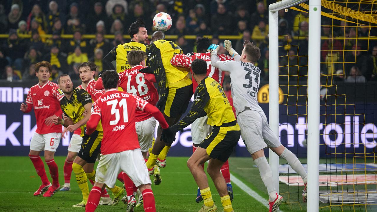 Das Bild zeigt zwei Gruppen gegnerischer Fußballspieler vor einem Towart im Fünf-Meter-Raum seines Tores. Einer er Spieler setzt sich gegen die anderen durch und erzeilt per Kopf einen Treffer.