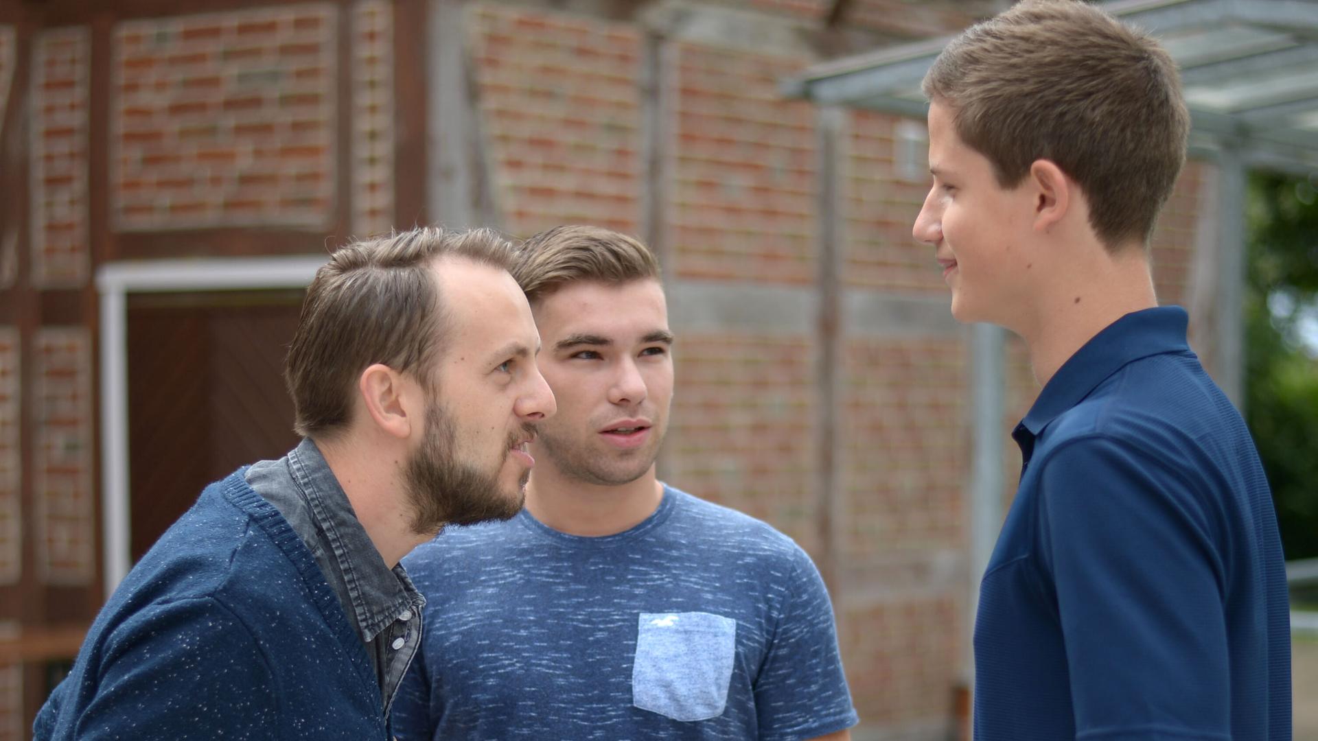 Ein Therapeut macht mit zwei jungen Männern, die an Stottern leiden, in einer simulierten Gesprächssituation eine Sprechübung.