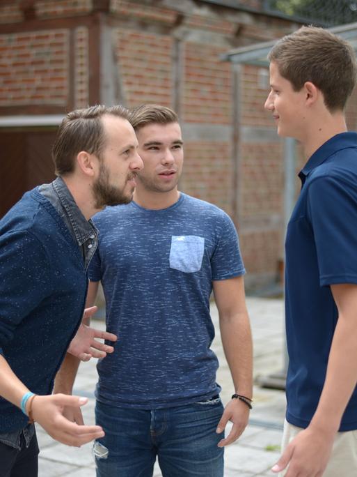 Ein Therapeut macht mit zwei jungen Männern, die an Stottern leiden, in einer simulierten Gesprächssituation eine Sprechübung.