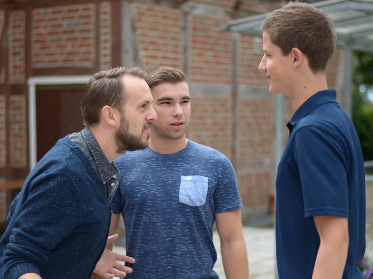 Ein Therapeut macht mit zwei jungen Männern, die an Stottern leiden, in einer simulierten Gesprächssituation eine Sprechübung.