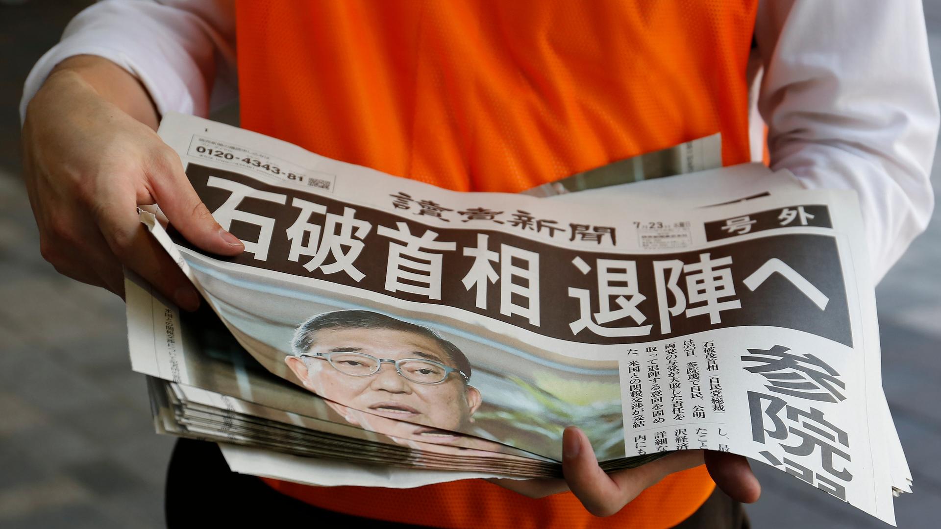 Eine Sonderausgabe einer Zeitung berichtet über den bevorstehenden Rücktritt des japanischen Premierministers Shigeru Ishiba. Ein Mensch hält eine Zeitung mit japanischen Schriftzeichen im Arm. Auf der Titelseite ist zudem ein Foto von Ishiba.