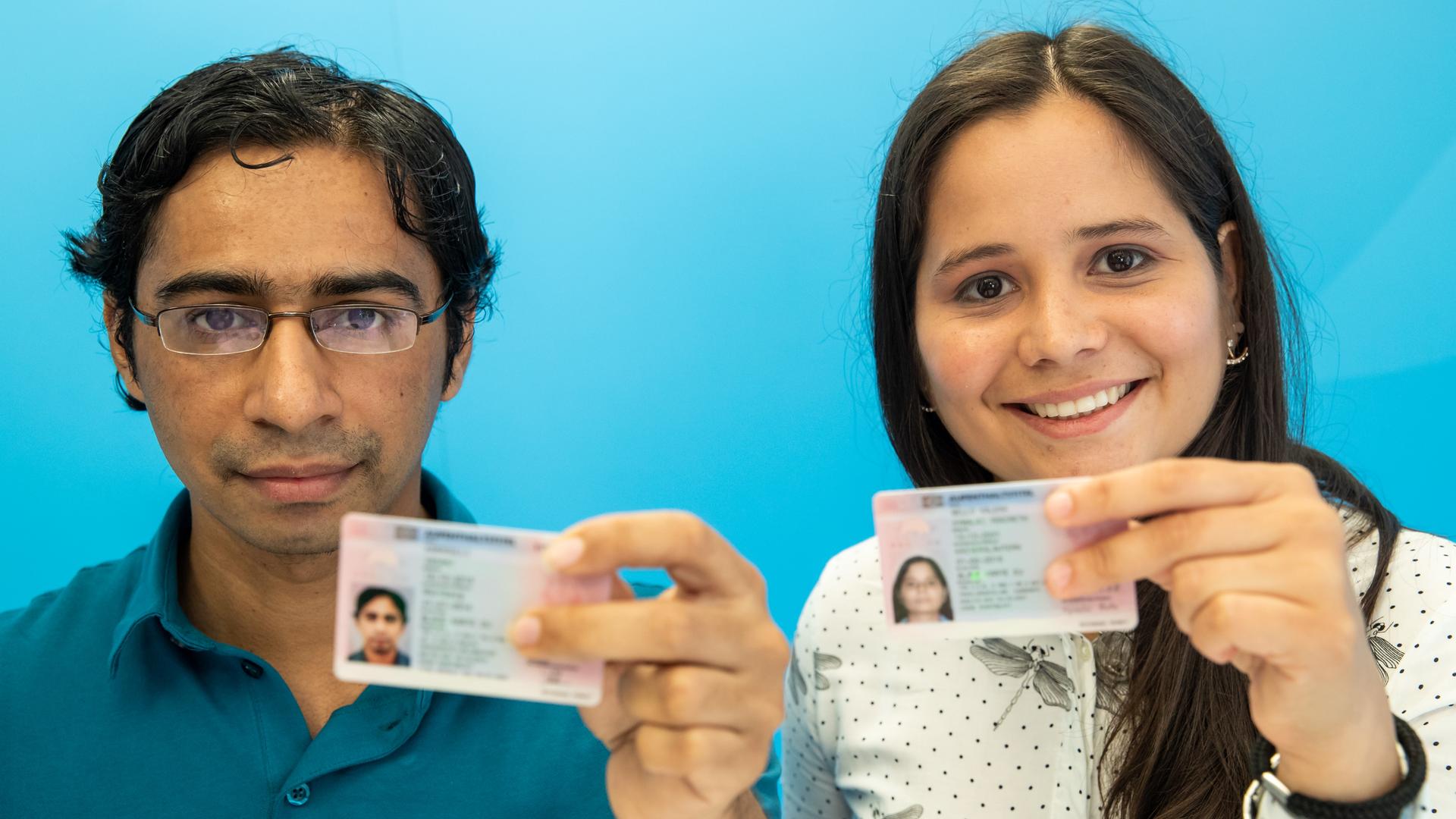 Zwei junge Leute mit der "Blauen Karte" für ausländische Fachkräfte. 