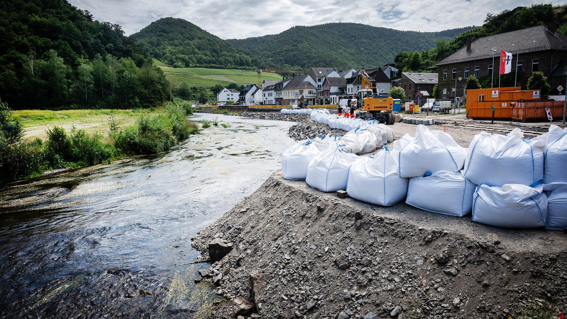 Sandsäcke sind am Ufer der Ahr aufgetürmt. Im Hintergrund die hügelige Landschaft. Sandsäcke sind am Ufer der Ahr aufgetürmt. Im Hintergrund die hügelige Landschaft.