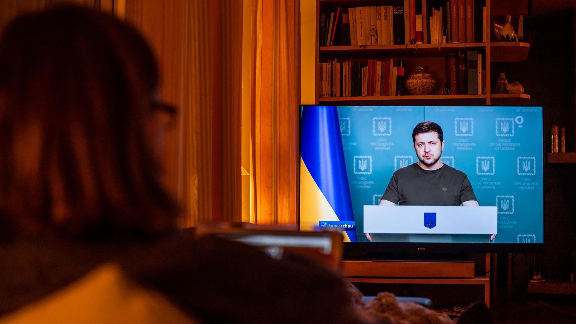 Eine Frau sitzt auf dem Sofa und schaut im Fernsehen die Tagesschau. Eine Frau sitzt auf dem Sofa und schaut im Fernsehen die Tagesschau.