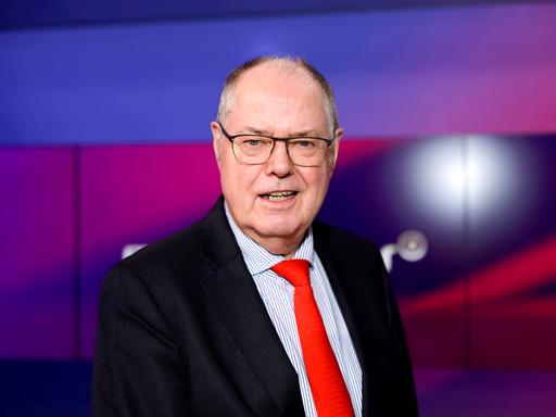 Das Bild zeigt ein Portrait des ehemaligen Bundesfinanzministers Peer Steinbrück, der in einem Fernsehstudio steht. 