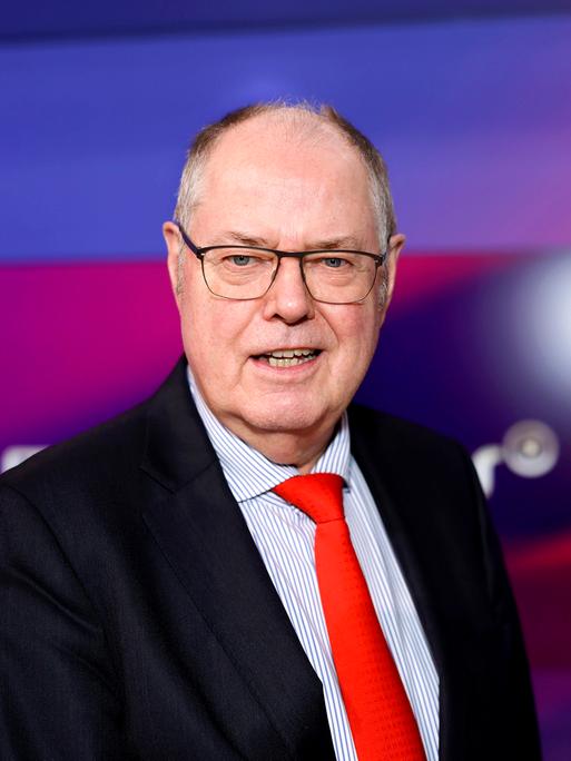 Das Bild zeigt ein Portrait des ehemaligen Bundesfinanzministers Peer Steinbrück, der in einem Fernsehstudio steht. 