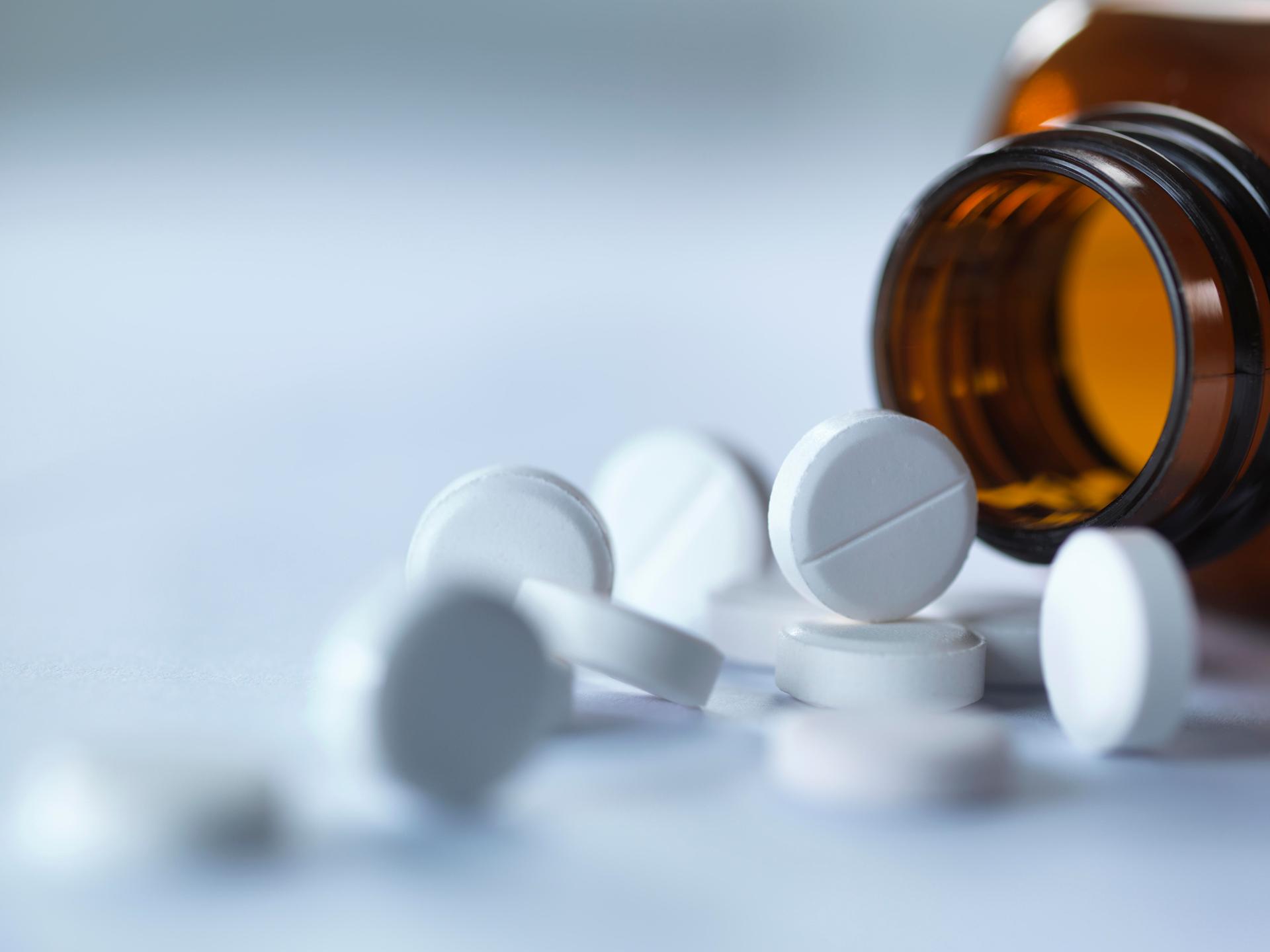 Tabletten liegen vor einem Tablettenglas