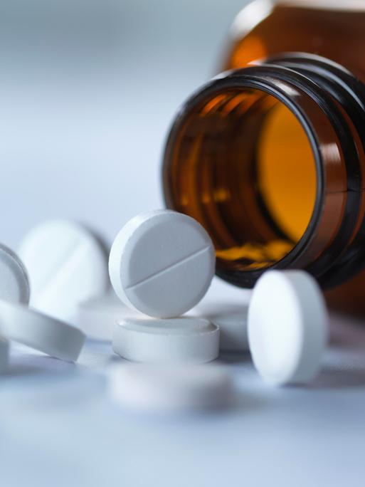 Tabletten liegen vor einem Tablettenglas