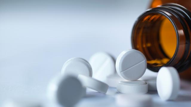 Tabletten liegen vor einem Tablettenglas