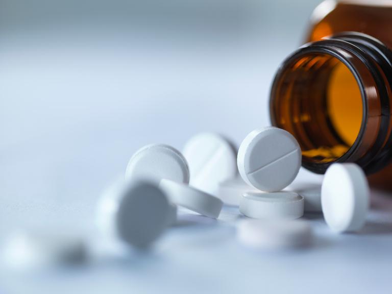 Tabletten liegen vor einem Tablettenglas