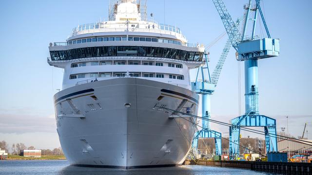 Ein riesiges Kreuzfahrt-Schiff liegt vor der Meyer-Werft. An der Seite von dem Schiff stehen große Kräne. 