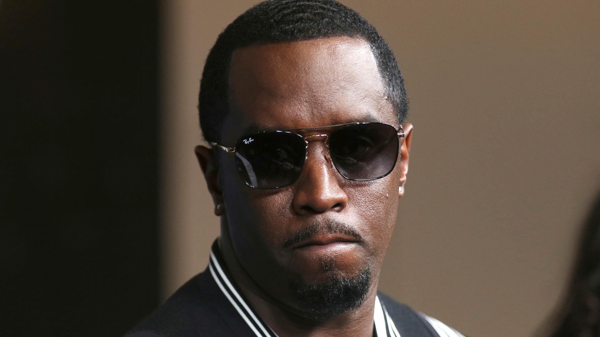 Sean „Diddy“ Combs kommt in dunkler Sonnenbrille und einer schwarz-weissen Collegejacke zur LA-Premiere von "The Four: Battle For Stardom" im CBS Radford Studio Center 2018, in Los Angeles. Seine Miene ist ernst, die Lippen aufeinander gespresst. Sean „Diddy“ Combs kommt in dunkler Sonnenbrille und einer schwarz-weissen Collegejacke zur LA-Premiere von "The Four: Battle For Stardom" im CBS Radford Studio Center 2018, in Los Angeles. Seine Miene ist ernst, die Lippen aufeinander gespresst.