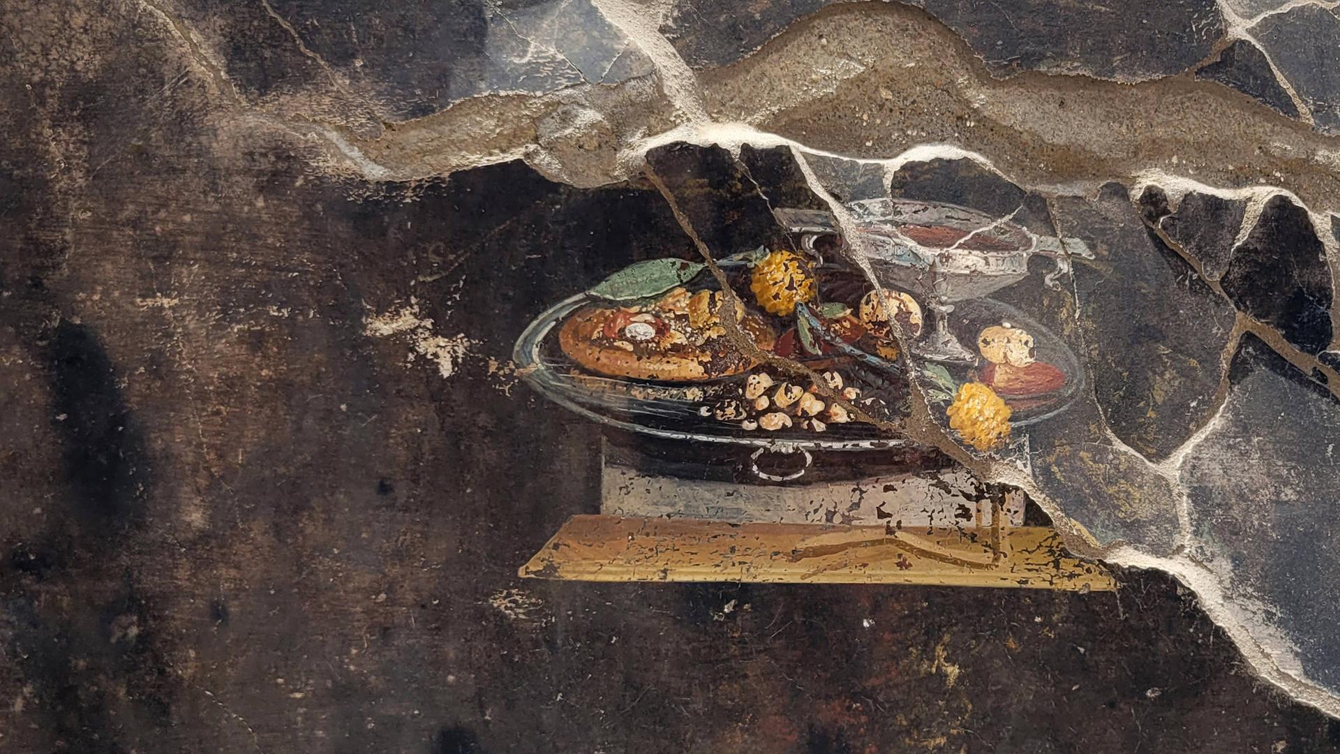 Ein Fresko in Pompeji zeigt möglicherweise die Abbildung eines Vorläufers der modernen Pizza. Ein belegter Teigfladen, allerdings ohne Tomaten und Käse, ist auf dem rund 2.000 Jahre alten Gemälde zu sehen.