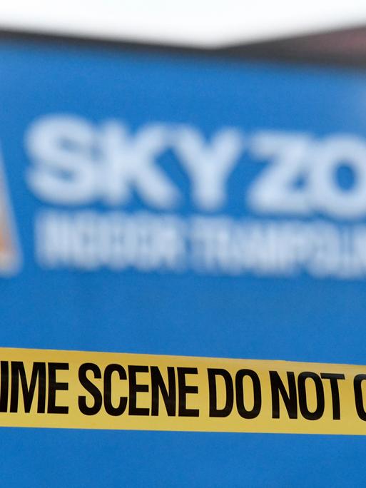 Eine gelbes Plastikband, auf dem "Crime Scene" steht, gespannt vor einem Tatort