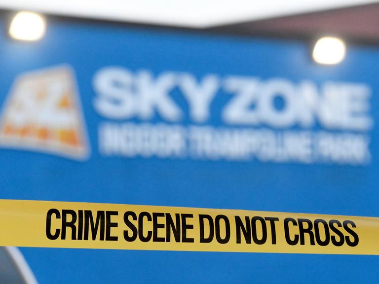 Eine gelbes Plastikband, auf dem "Crime Scene" steht, gespannt vor einem Tatort