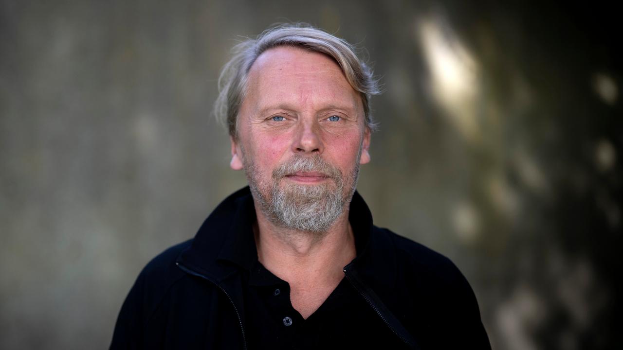 Der Schriftsteller und Journalist Jens Balzer im Portrait mit grauem Bart vor dunklem Hintergrund. 