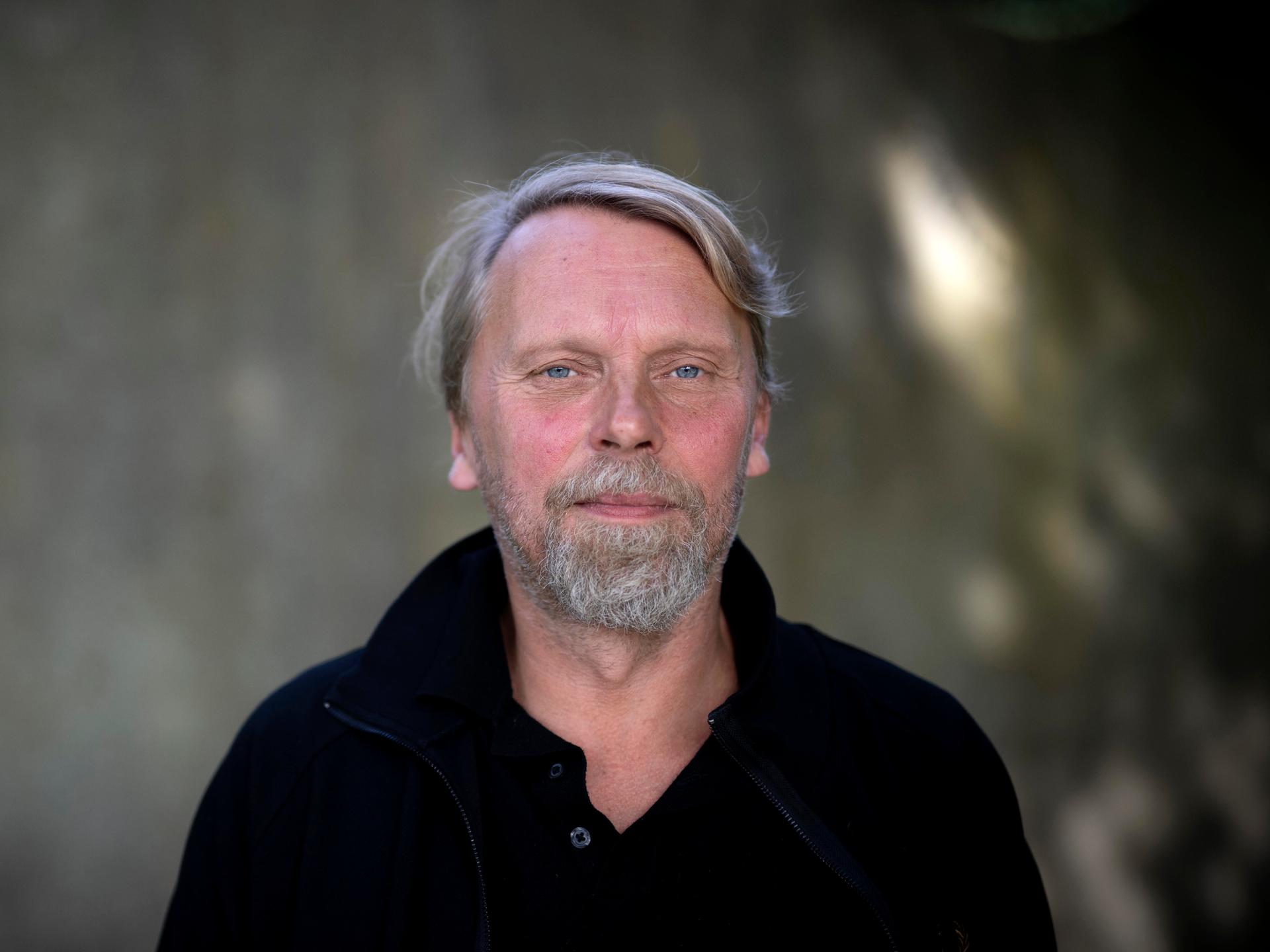 Der Schriftsteller und Journalist Jens Balzer im Portrait mit grauem Bart vor dunklem Hintergrund. Der Schriftsteller und Journalist Jens Balzer im Portrait mit grauem Bart vor dunklem Hintergrund.