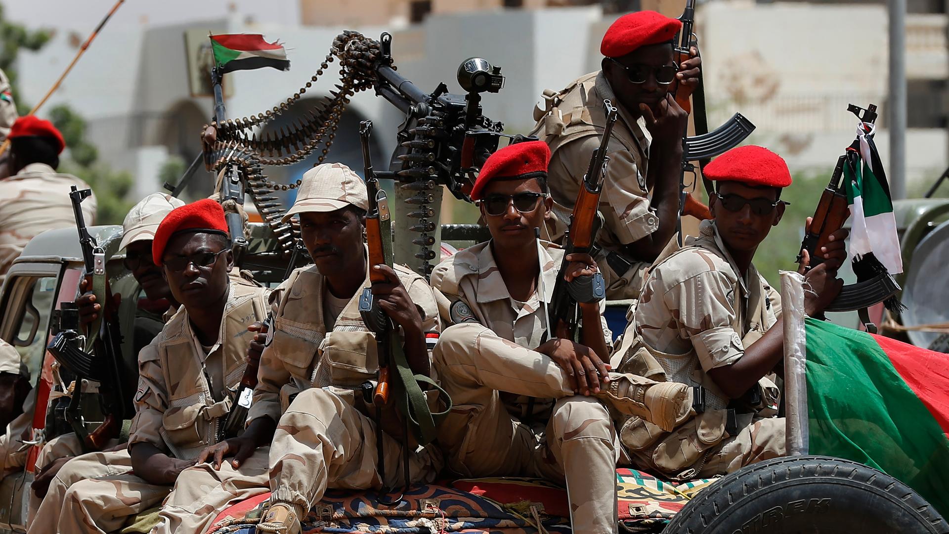 Sudanesische Soldaten einer paramilitärischen Einheit sitzen auf einem Laster. Sie tragen Tarnuniformen, rote Mützen und halten Gewehre in den Händen. Sudanesische Soldaten einer paramilitärischen Einheit sitzen auf einem Laster. Sie tragen Tarnuniformen, rote Mützen und halten Gewehre in den Händen.