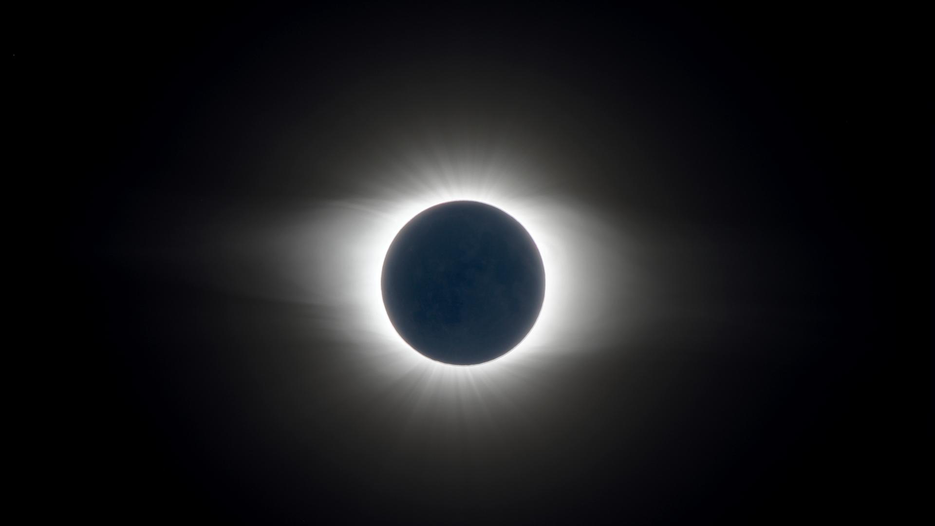 Aufnahme einer totalen Sonnenfinsternis, bei der sich die Sonnenkorona zeigt, da der Mond die Sonne komplett bedeckt.