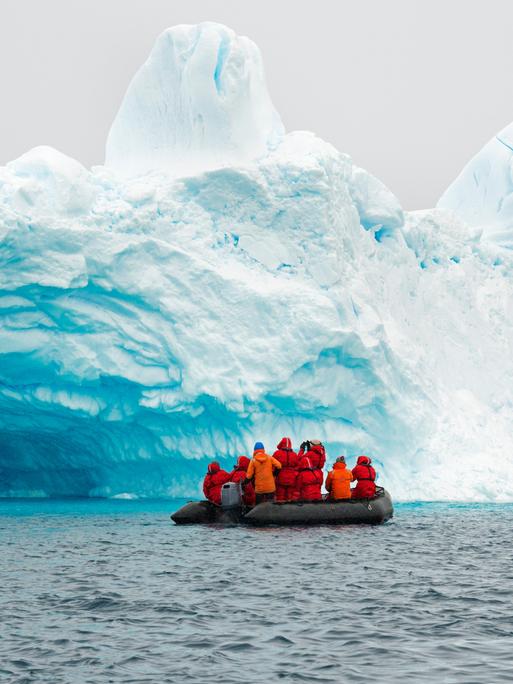 In der Antarktis fahren einige Forschende auf einem Gummiboot am Rand eines Eisbergs entlang. In der Antarktis fahren einige Forschende auf einem Gummiboot am Rand eines Eisbergs entlang.
