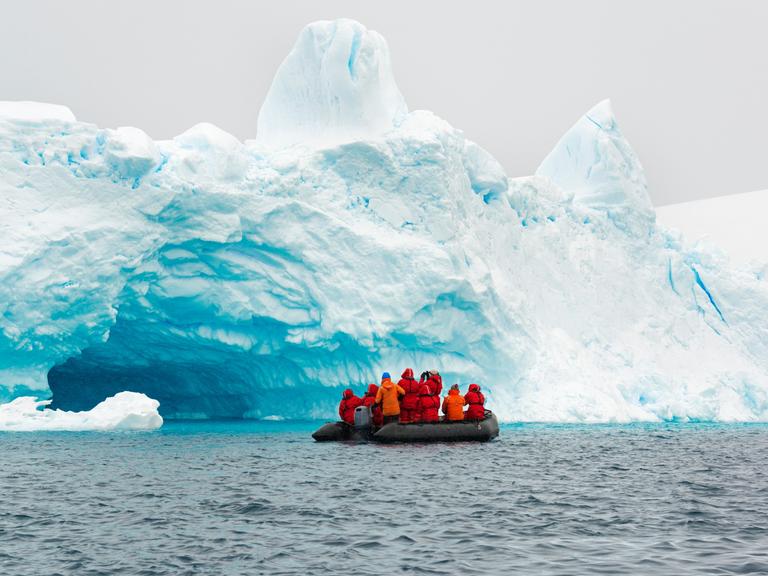In der Antarktis fahren einige Forschende auf einem Gummiboot am Rand eines Eisbergs entlang. In der Antarktis fahren einige Forschende auf einem Gummiboot am Rand eines Eisbergs entlang.