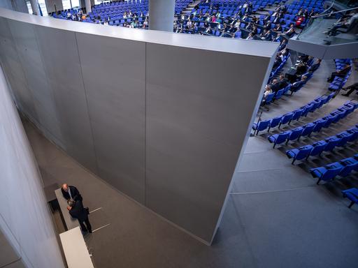 Bundeskanzler Olaf Scholz (SPD), spricht hinter der Rückwand des Plenarsaal mit Rolf Mützenich, Vorsitzender der SPD-Bundestagsfraktion, in der Debatte zum Sicherheitspaket.