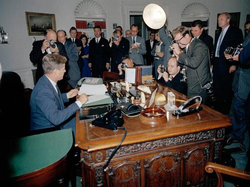 Präsident John F. Kennedy während der Kuba-Krise, umringt von Reportern im Weißen Haus.