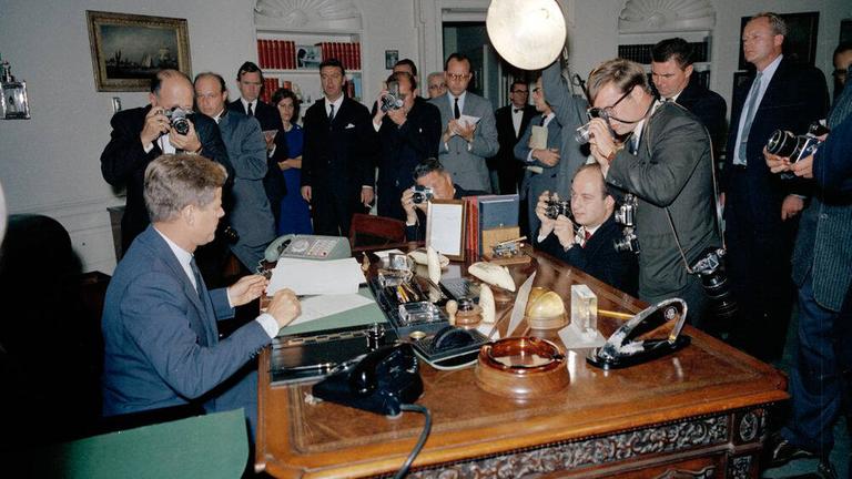 Präsident John F. Kennedy während der Kuba-Krise, umringt von Reportern im Weißen Haus.