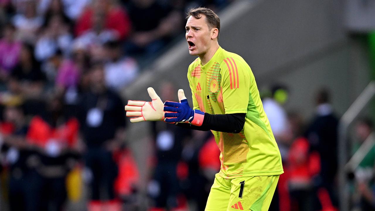 Neuer im gelben Trkot klatscht motivierend in die Hände. Dahinter unscharf eine vollbesetzte Tribüne.