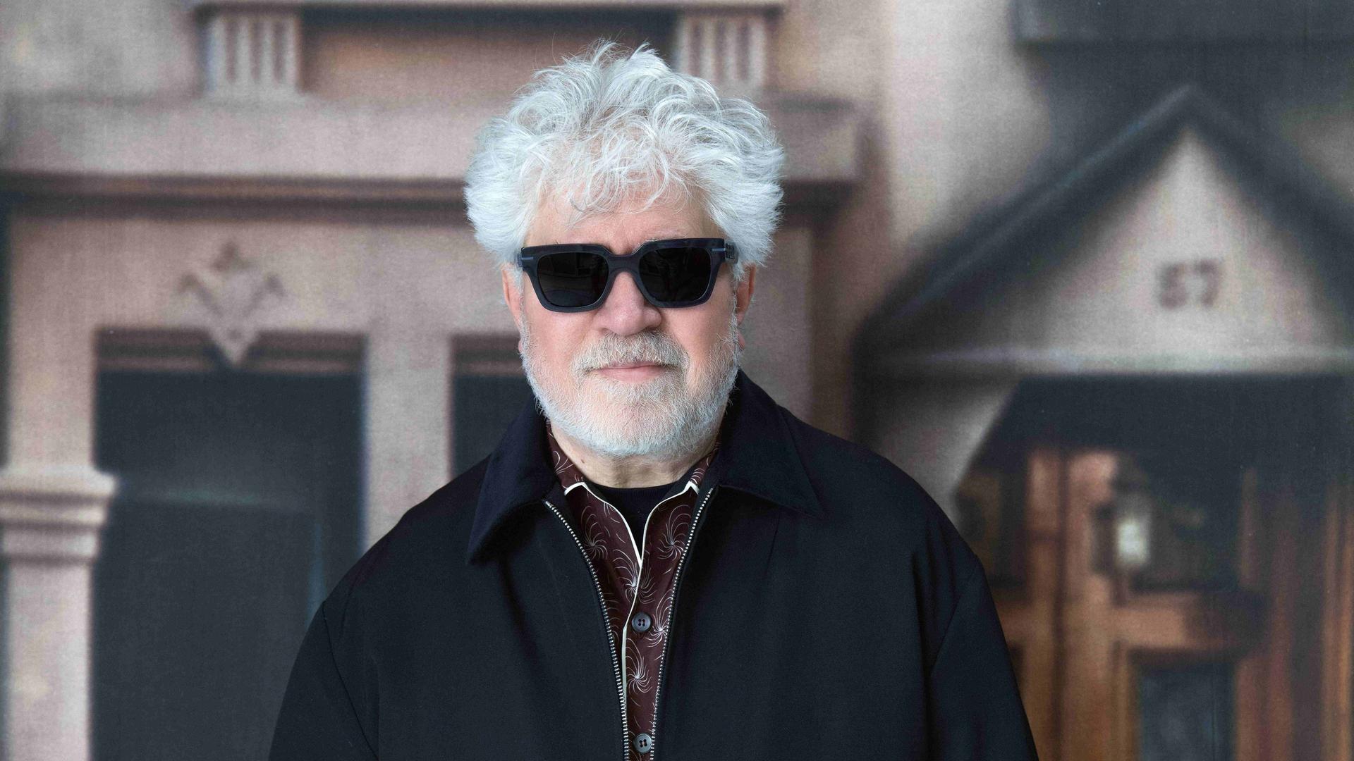 Der spanische Filmregisseur Pedro Almodóvar steht vor einem Plakat. Er trägt eine schwarze Sonnenbrille, sein grauweißes Haar sieht leicht lockig und wuschelig aus, er trägt einen kurzen, weißen Vollbart. Aufnahme vom 07.08.2024.