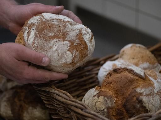 Ein Bäcker hält ein Brot.  