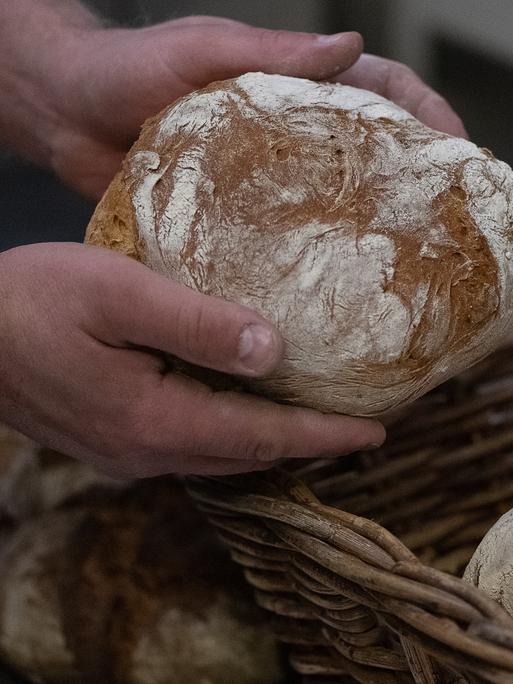 Ein Bäcker hält ein Brot.  